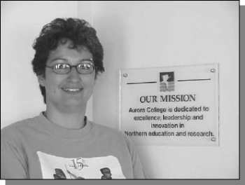 Photo of a woman beside a plaque mounted on a wall titled: Our Mission