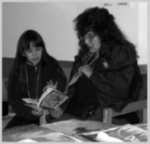 An female yout and a female adult reading from a book