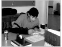 Male writing in a book at a desk