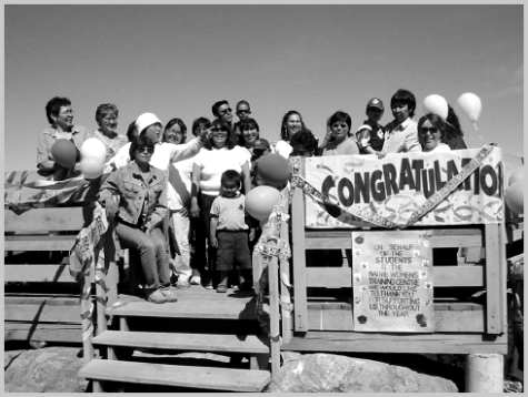 Large group of people on an outdoor platform with a sign that says: Congratulations