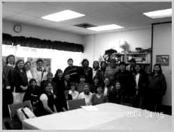 Large group of people sitting and standing around a big table