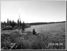 Two men fishing on the shore of a lake