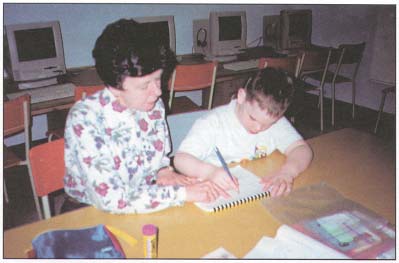 Picture of a woman helping a boy write