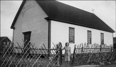 photo of a school house with a woman standing in front of it 