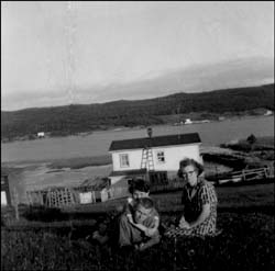 photo of a man, a woman and a child with a house in the background 