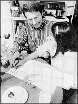 Older woman helping a girl to write