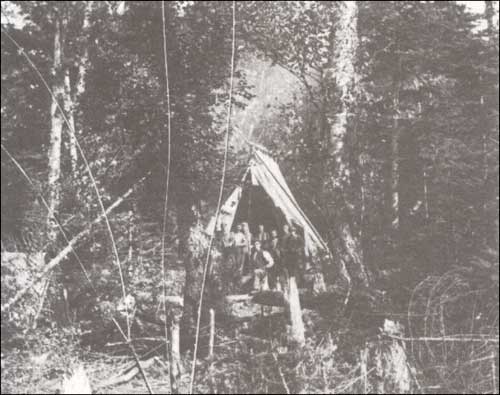 photo of several men in a tent in a forest setting