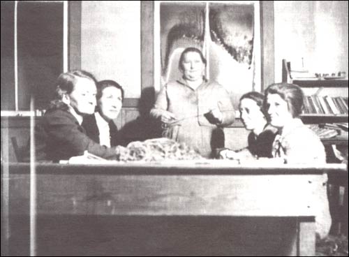 photo of five women around a table knitting and sewing