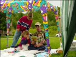 A male adult with three children under a tent canopy