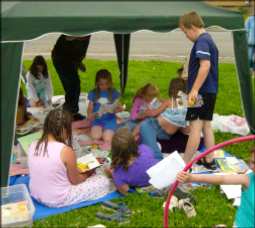 Adults and children under a tent canopy