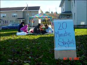 People under a tent canopy with sign: 20 Minute Storytents