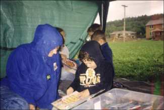Adult and children sheltering under a tent canopy