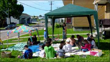 Children and adults in an outdoor setting under two tent canopies