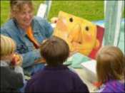 An adult showing three children a large poster