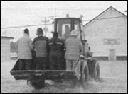 photo of a bulldozer driving through the flood in Badger