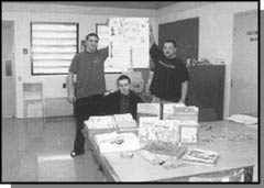 Graphic: a photograph of 3 people holding a sign in front of a desk