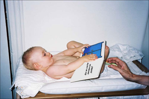 A baby looking at  images in a book