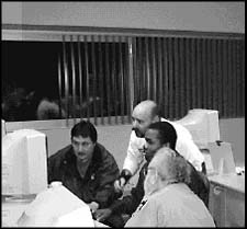 photo of four men looking at a computer monitor screen