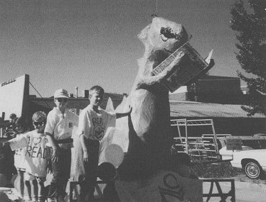 Kids posing witha a papier mache of a dinosaur