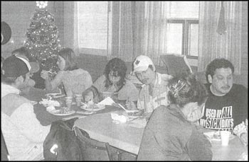 photo  of several people sitting at long tables and eating meals